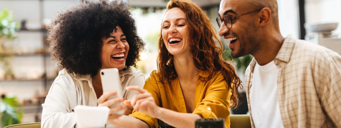 3 people looking at a phone and laughing