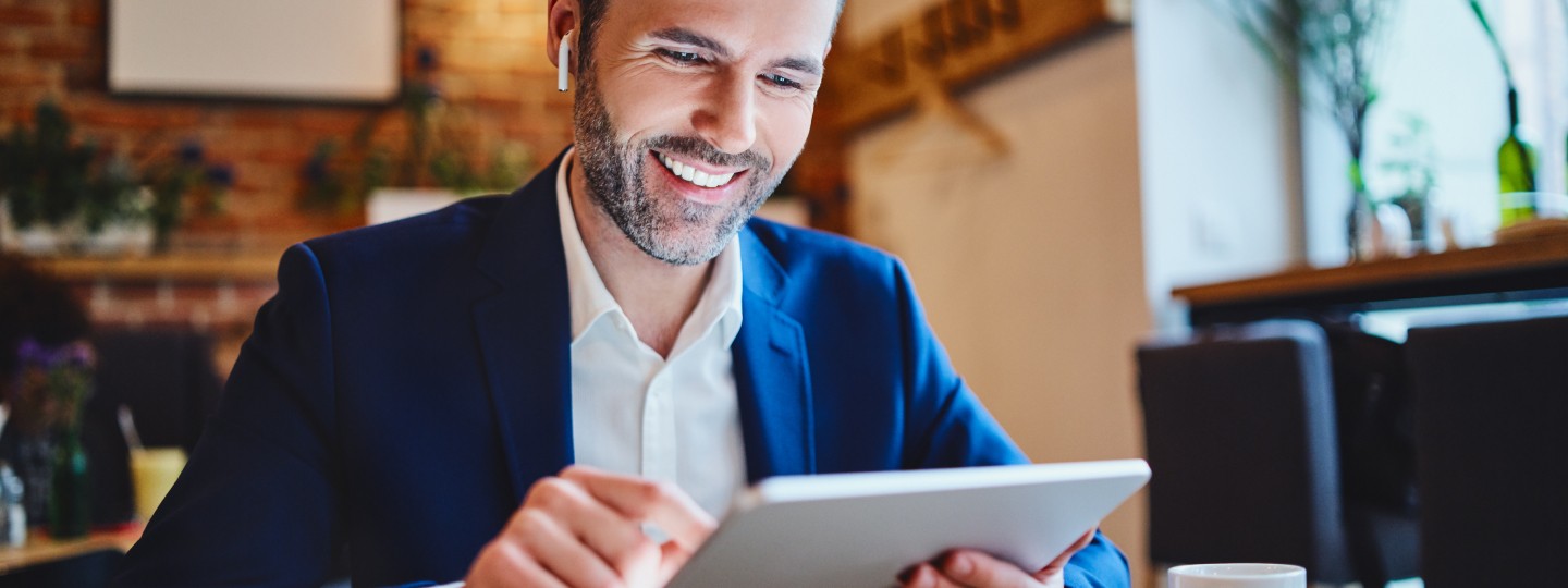 Man in coffee shop looking at a tablet